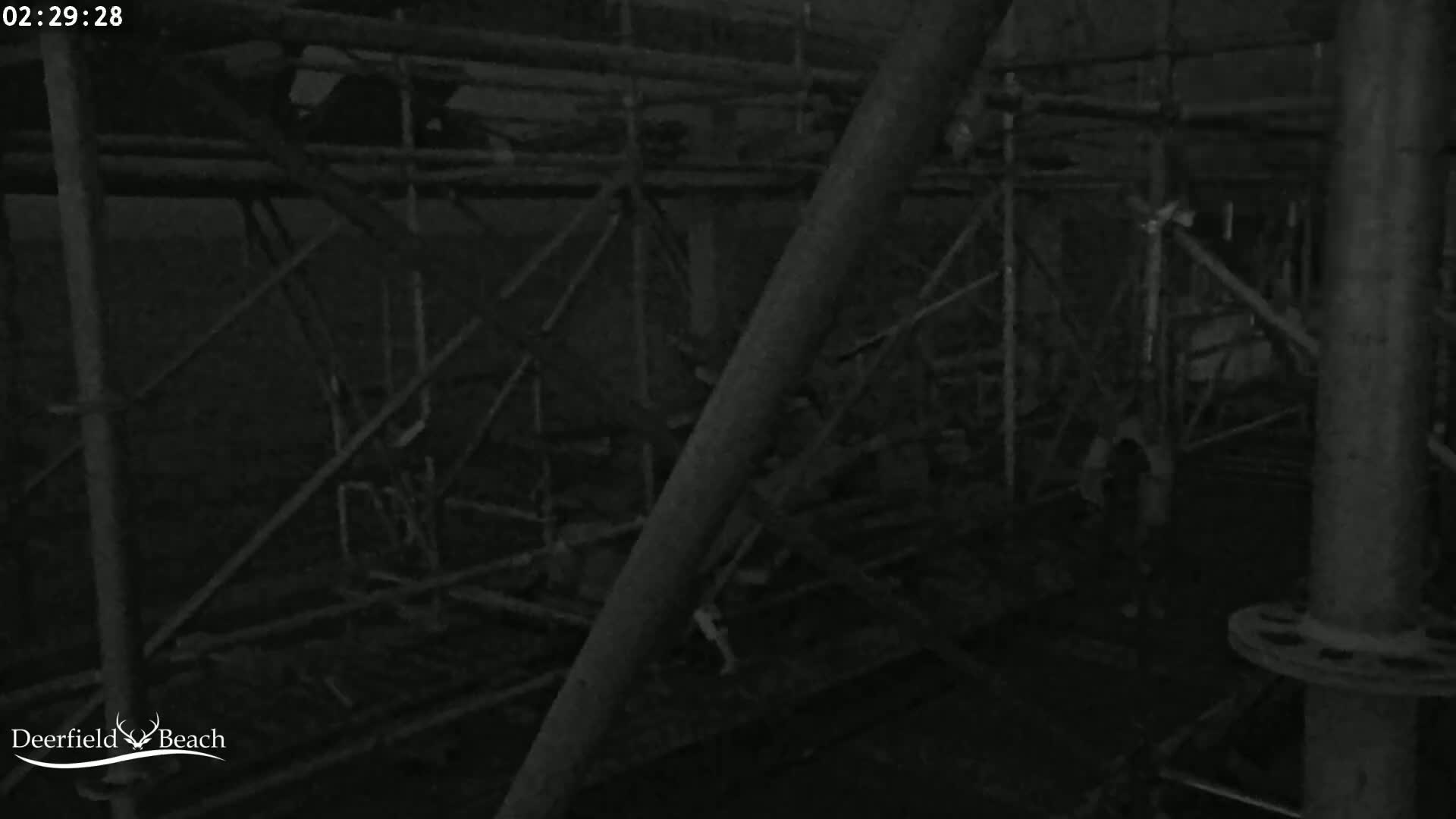 A dark, nighttime image shows a complex network of metal scaffolding.