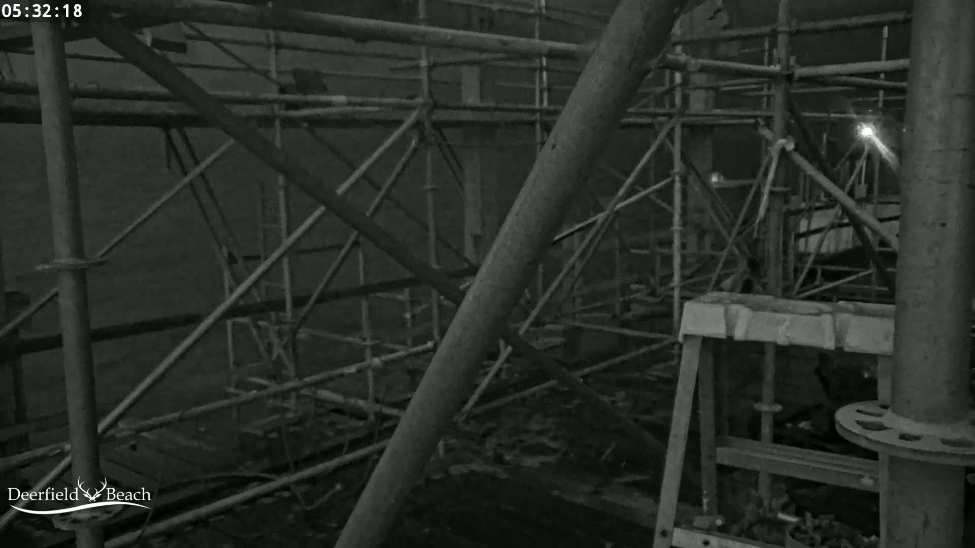 A nighttime, low-light image shows a complex network of metal scaffolding and support structures.
