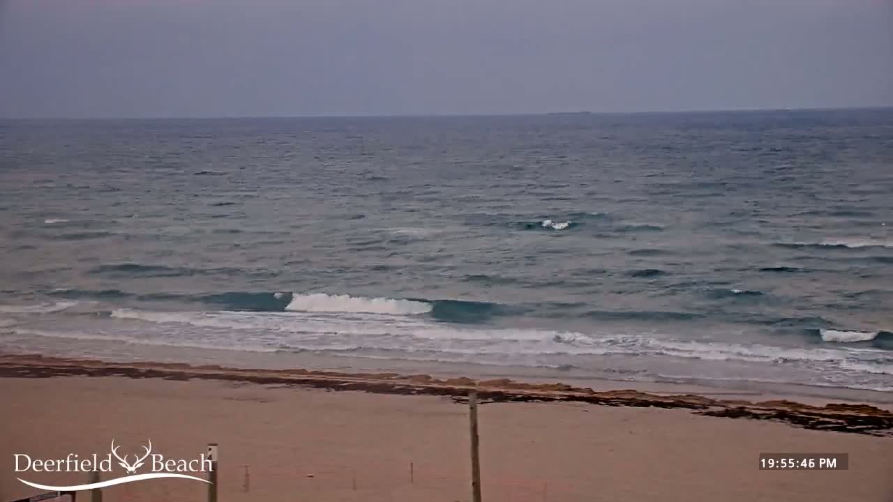 A sandy beach with small waves rolling onto the shore under an overcast sky.