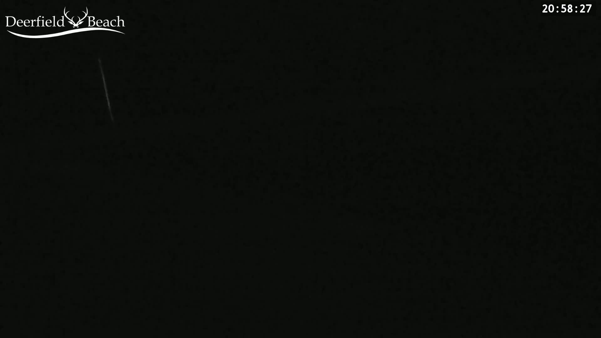 The image shows a completely dark nighttime scene with a faint, vertical, white streak.