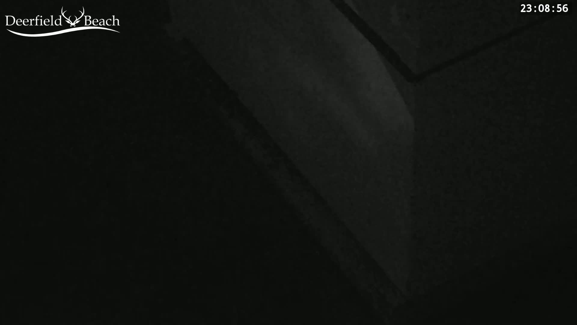 A dark, possibly nighttime, image shows a corner of a room or building with indistinct textures and shapes.