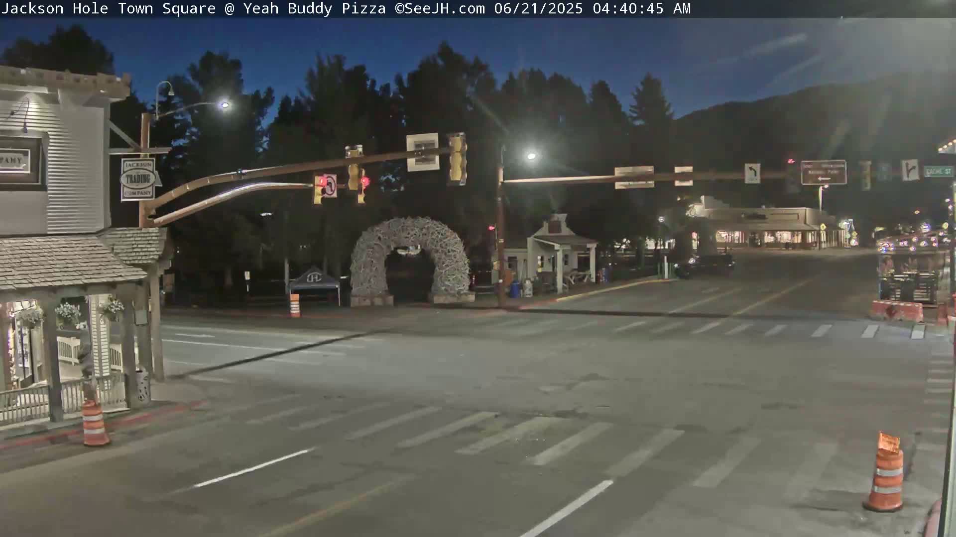 A mostly empty town square at night, under a dark blue sky, with a large antler archway in the center.