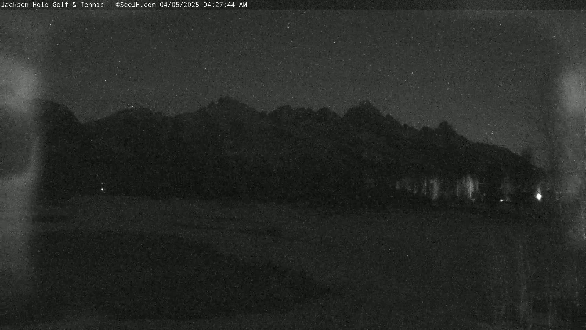 A nighttime view of silhouetted mountains under a starry sky.