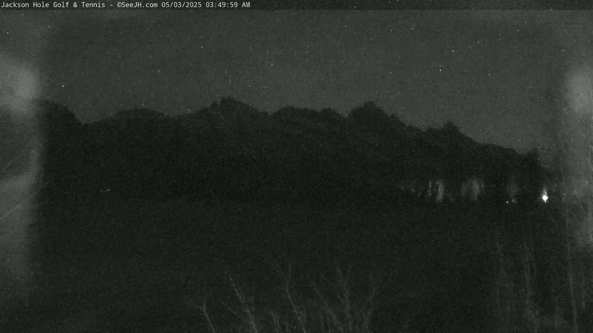 A nighttime view of dark mountains under a starry sky.