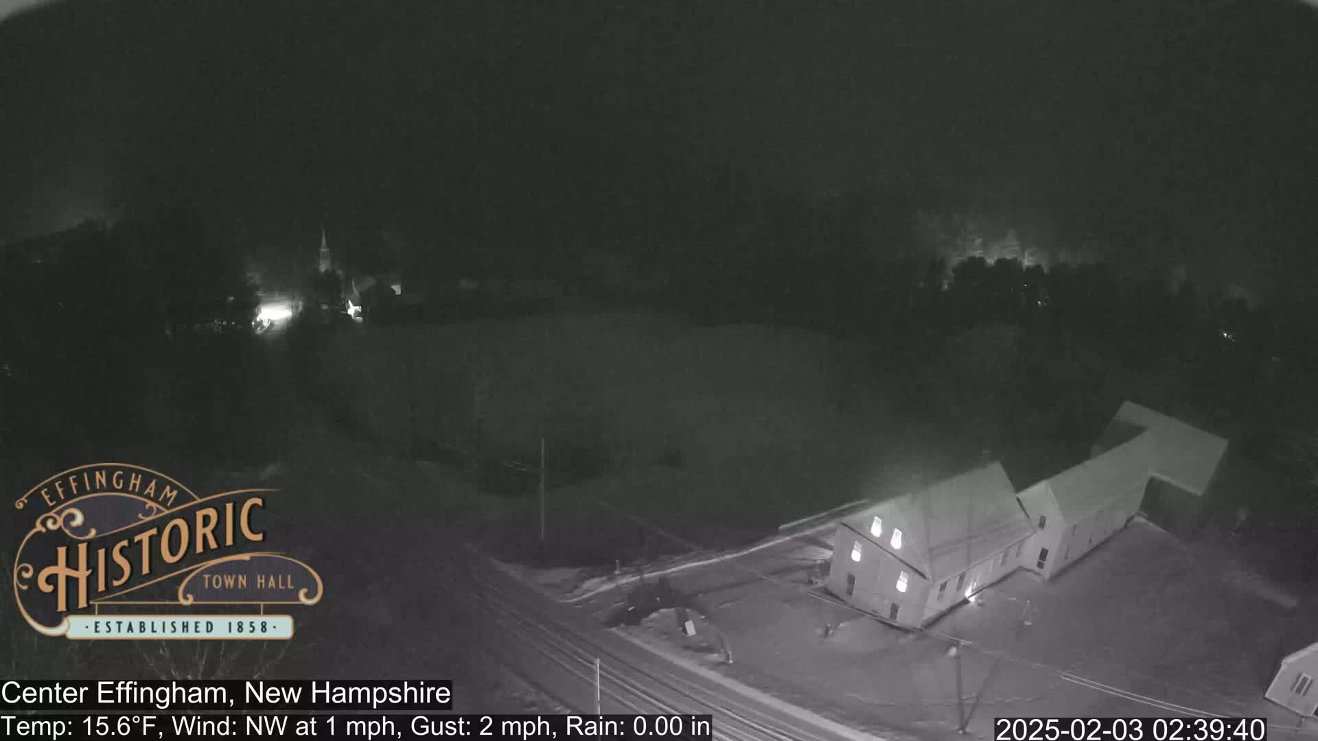 A nighttime, low-light view of a building and surrounding area under a dark sky with a temperature of 15.6°F, a northwest wind of 1 mph gusting to 2 mph, and no rain.