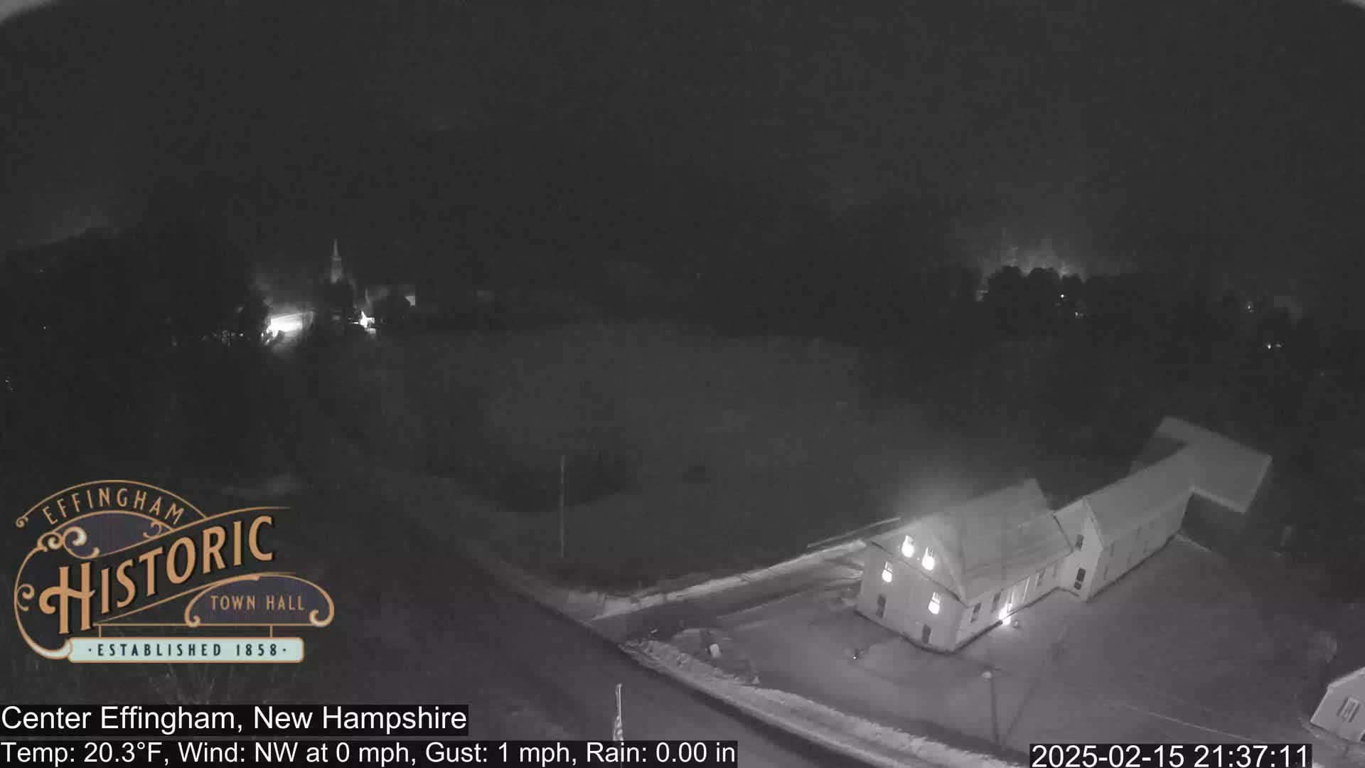 A nighttime, aerial view of a building and surrounding area, showing calm conditions with no rain.