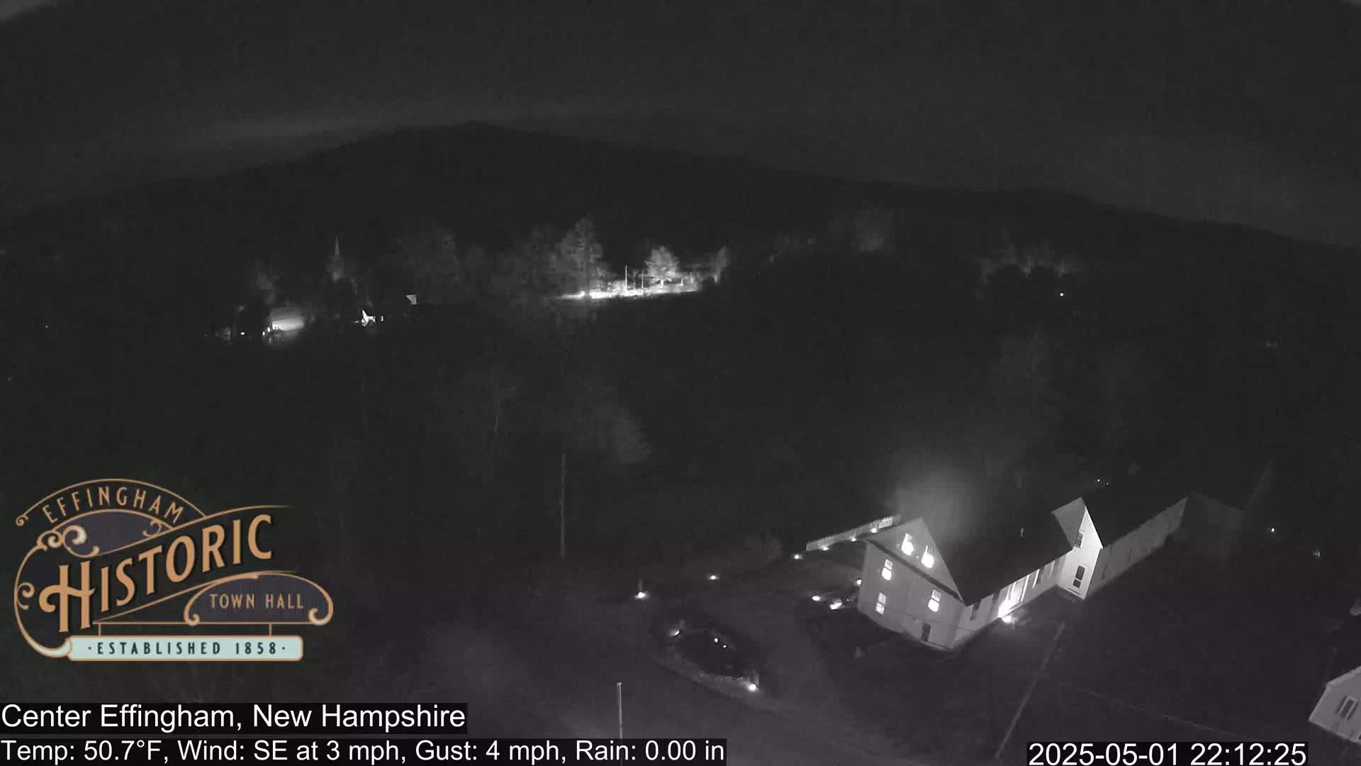 A nighttime aerial view shows a building complex and surrounding area with a light southeast wind.