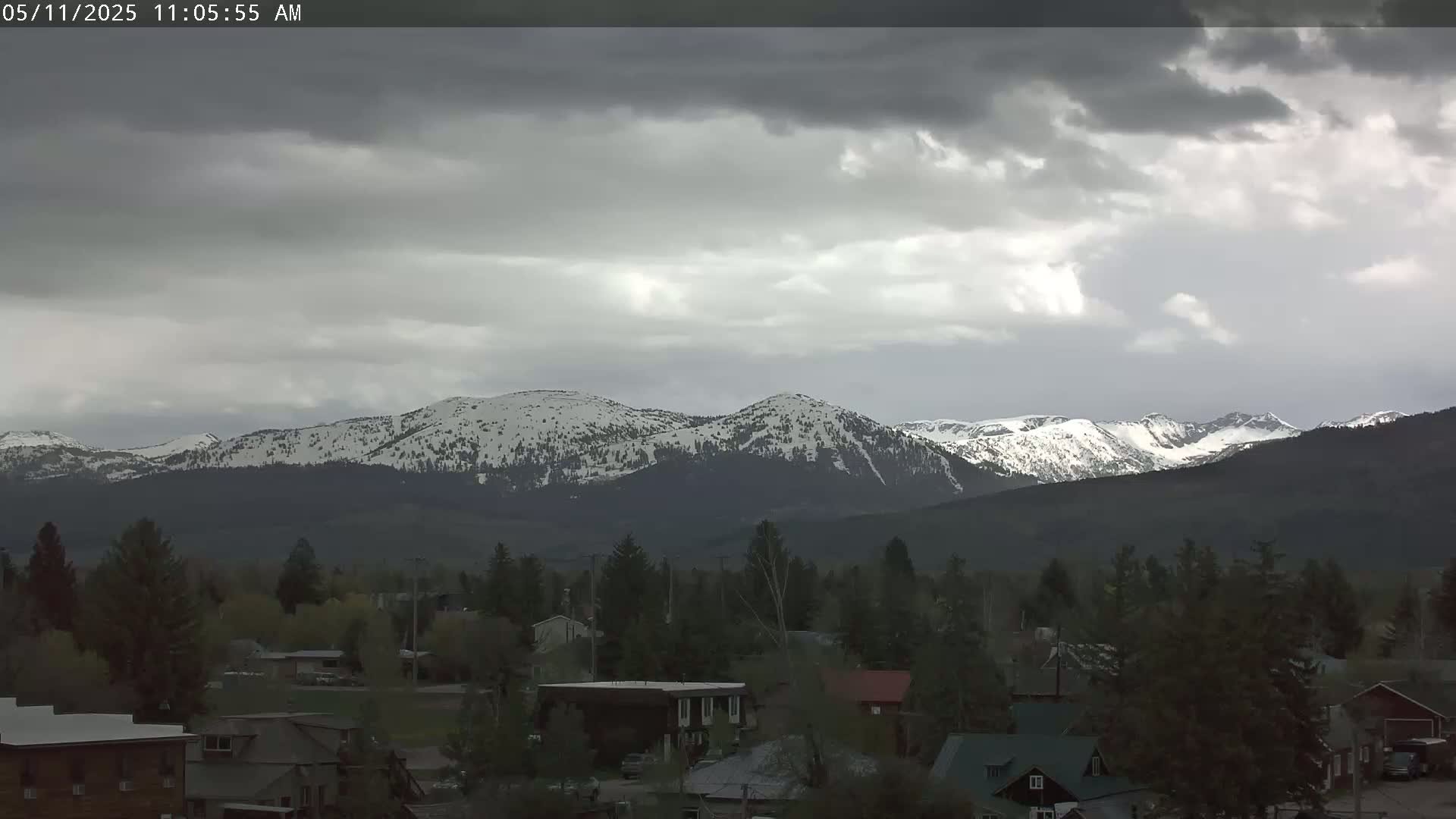 A snow-capped mountain range is visible in the distance behind a small town under an overcast sky.