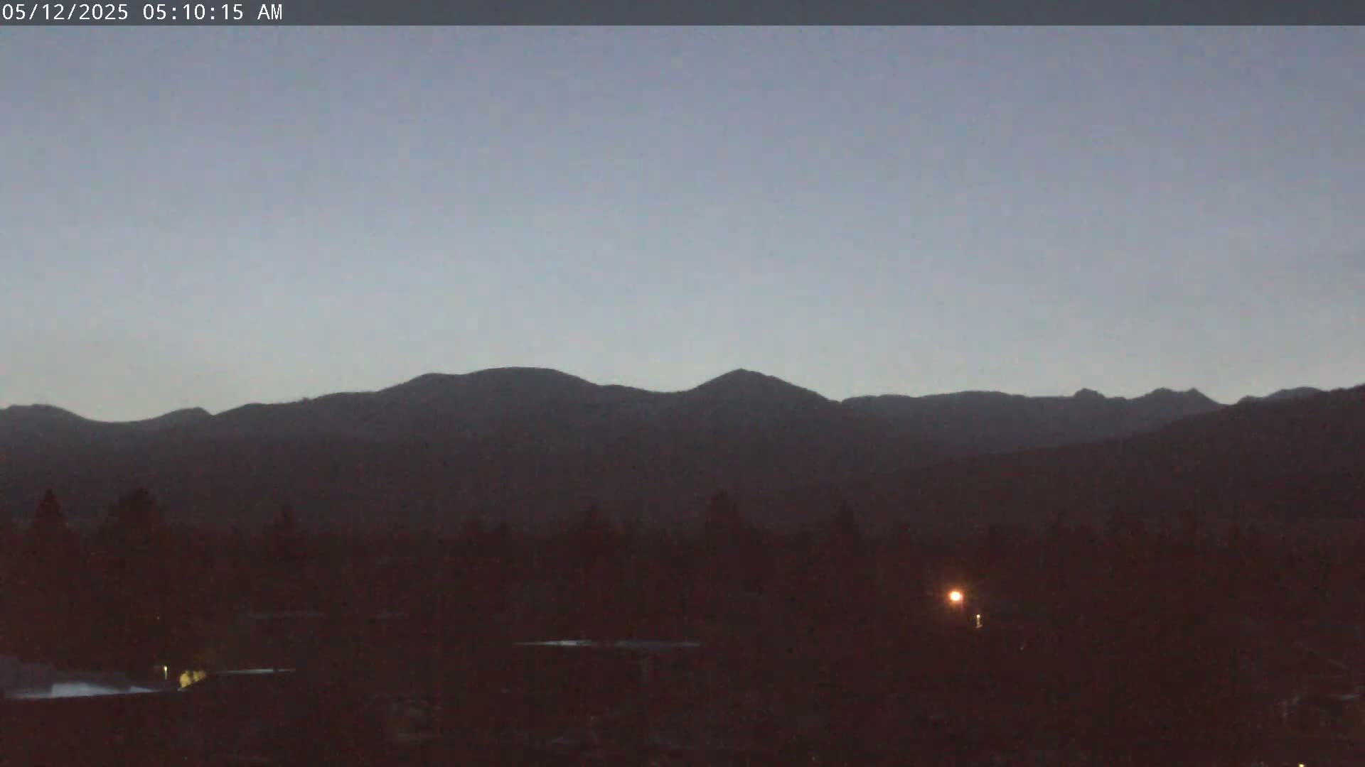 A dark, mountainous landscape is visible at dawn under a clear, pale sky.
