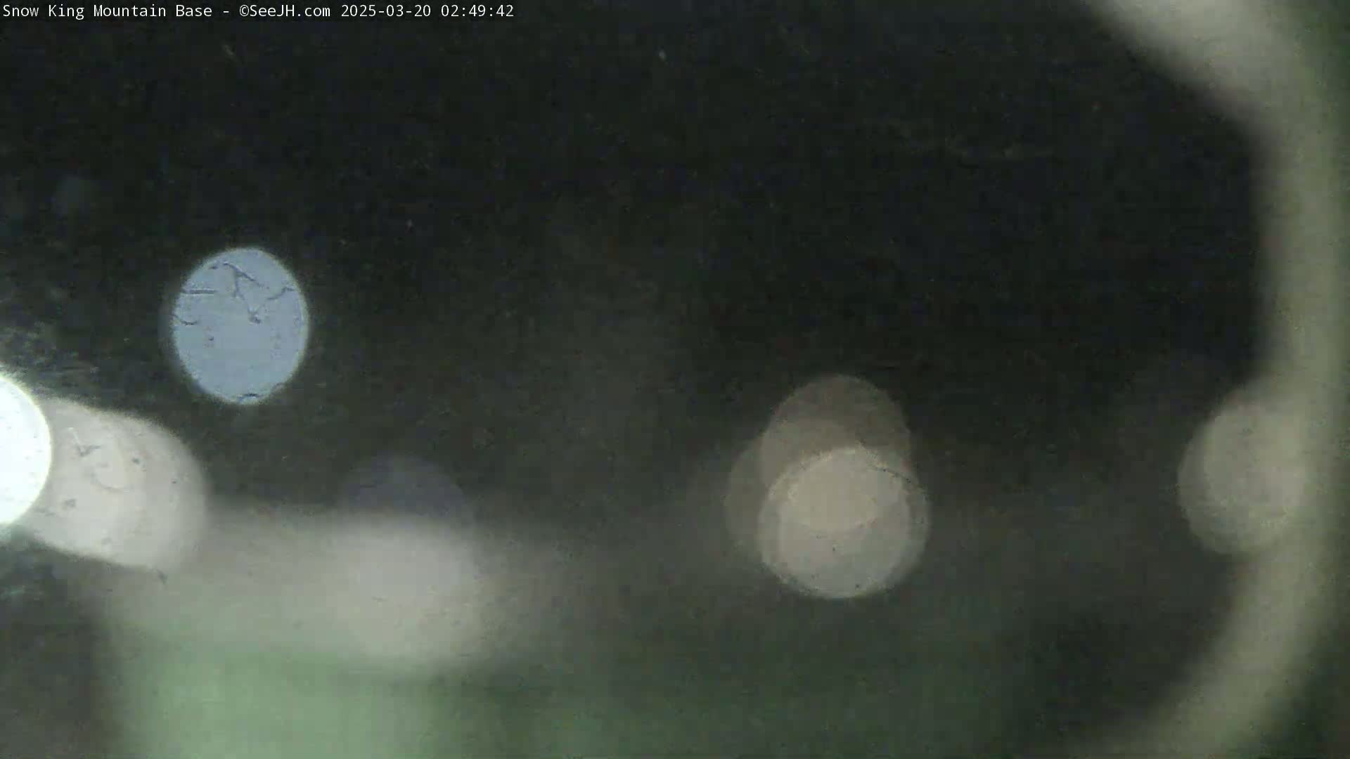 A blurry, nighttime image shows out-of-focus lights on a dark background.