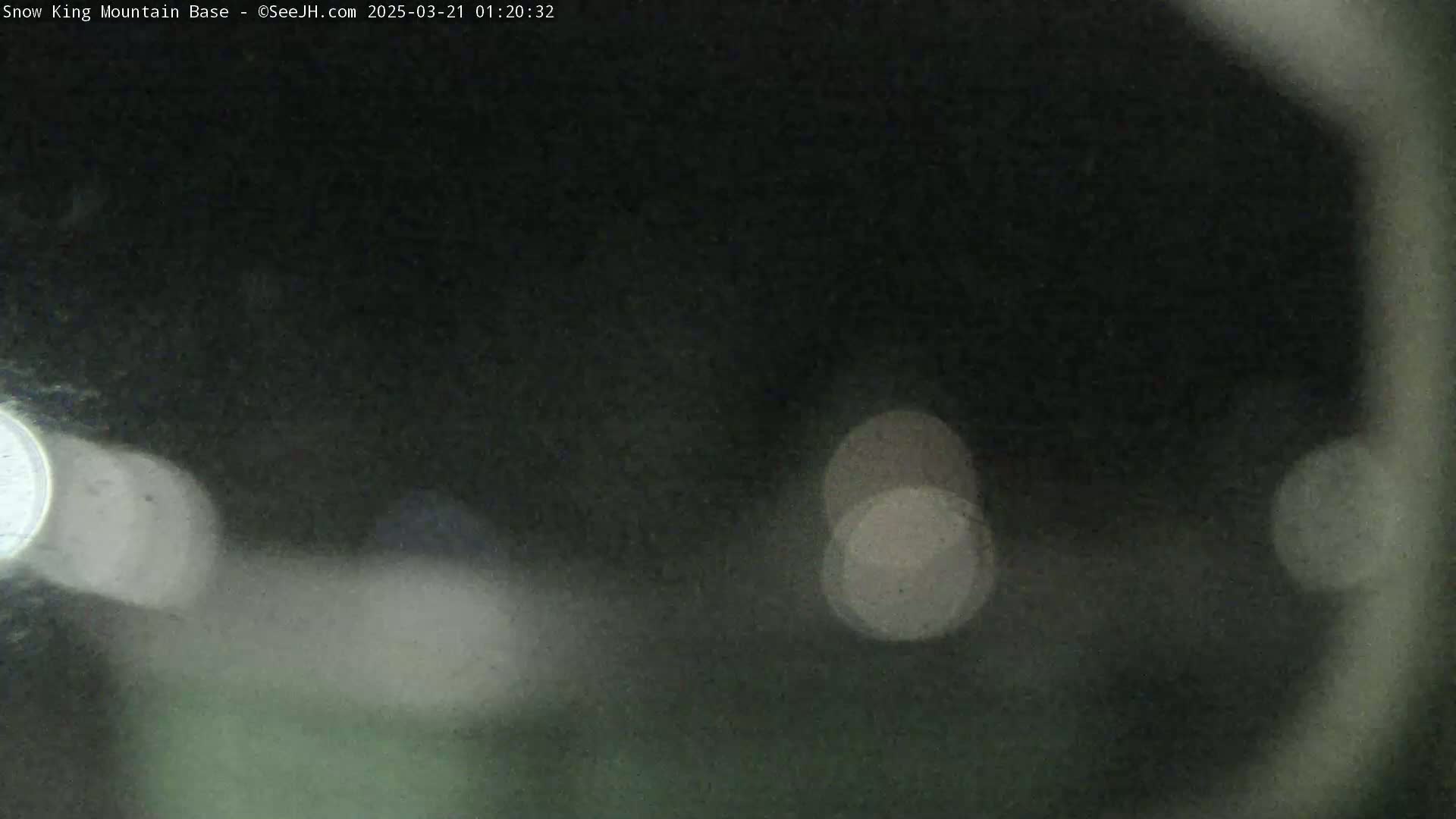 A dark, blurry nighttime scene with indistinct lights and a hazy atmosphere.