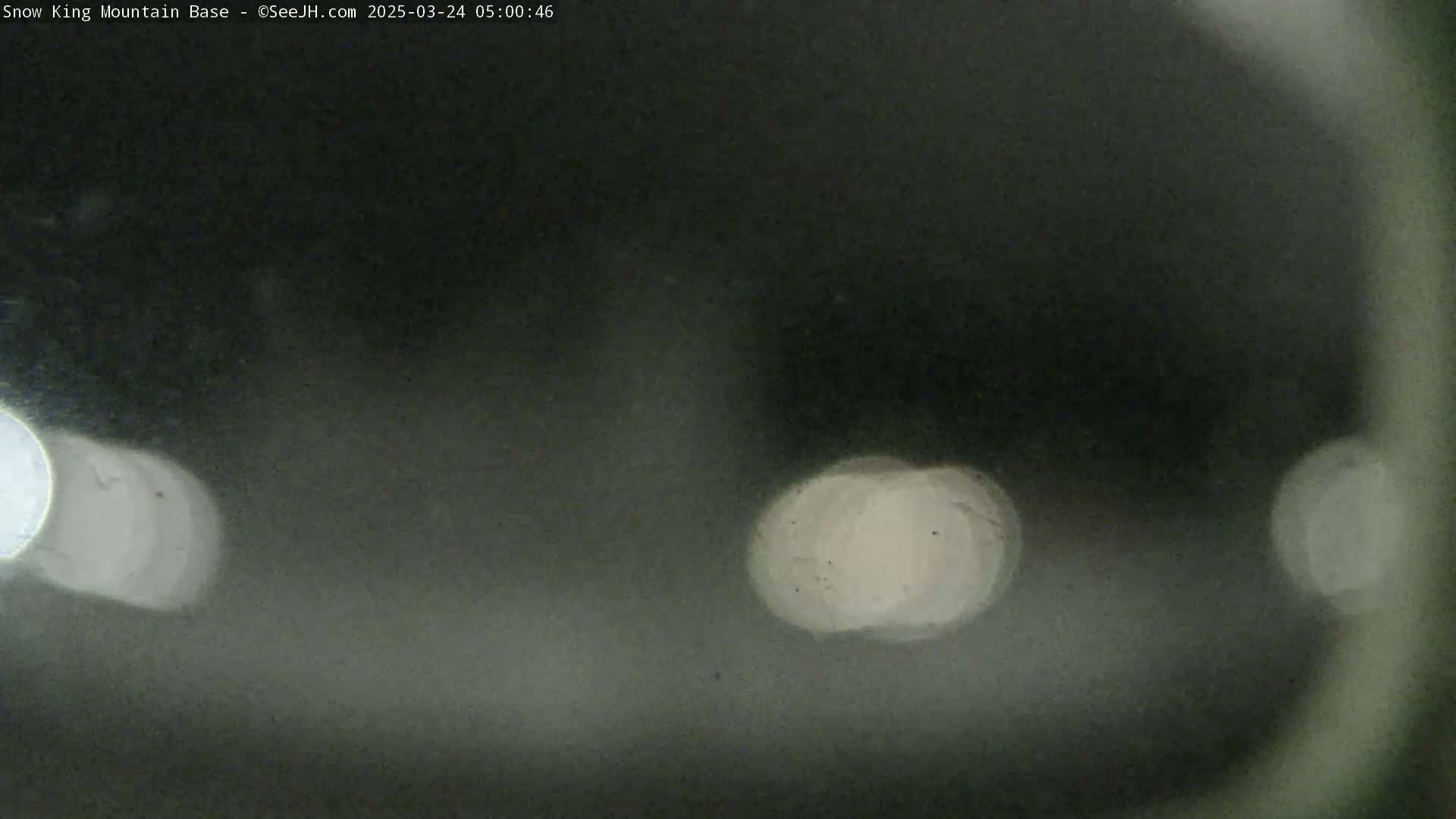 Blurred, out-of-focus nighttime images of light sources are visible through a hazy or snowy atmosphere.
