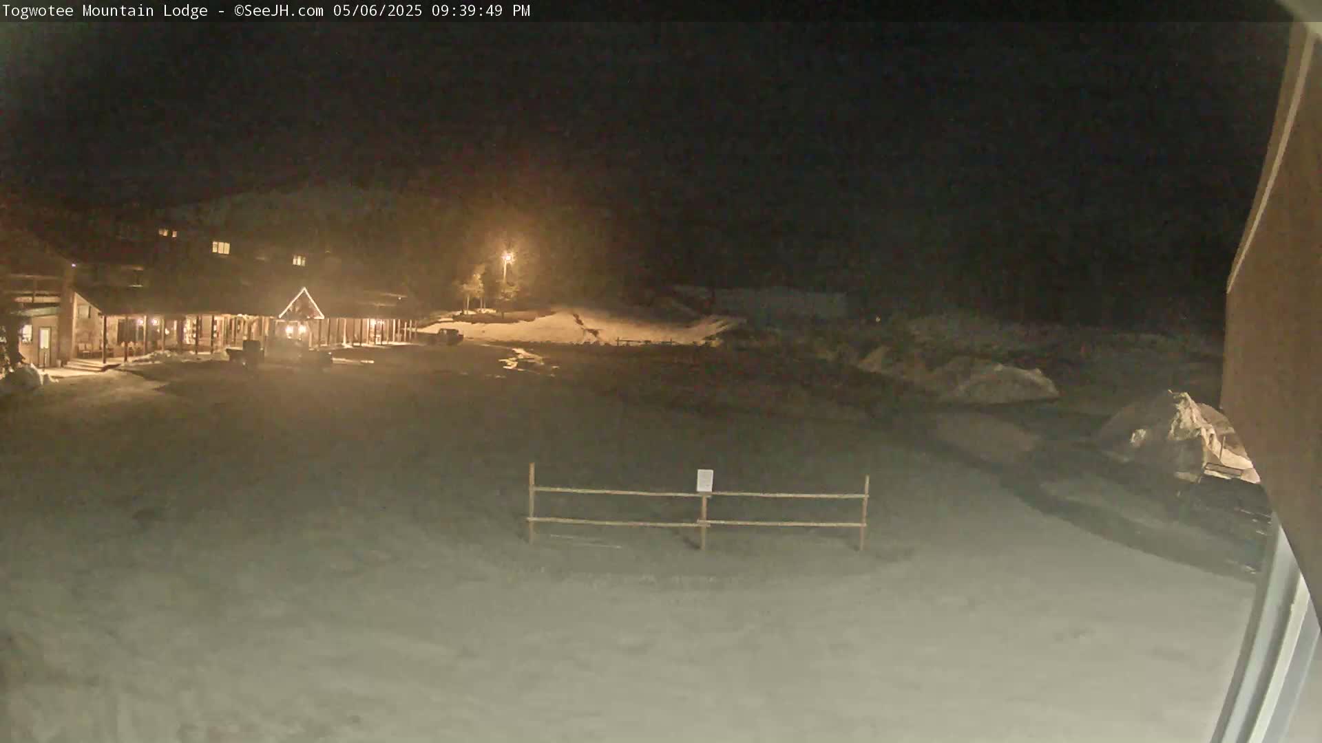 A lodge is illuminated at night in a snow-covered area under a dark sky.