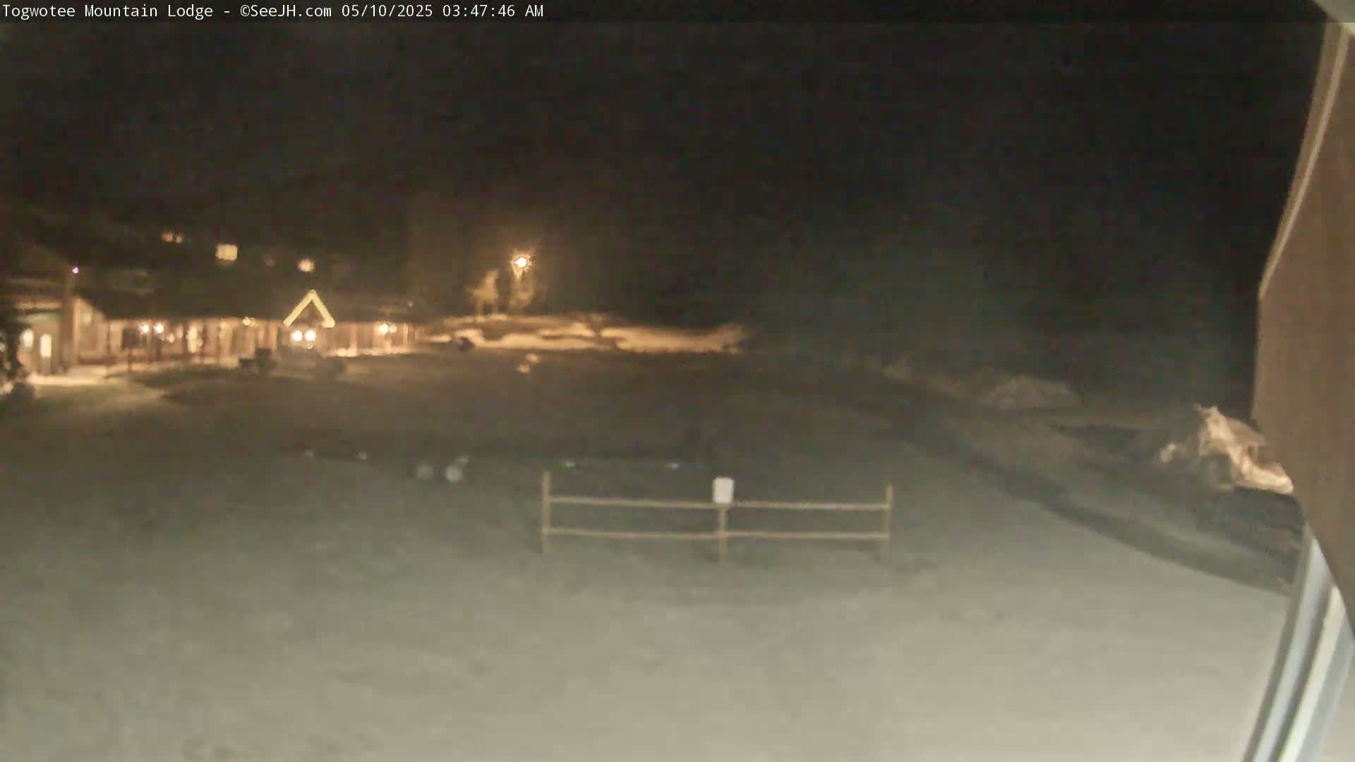 A snow-covered parking lot at night in front of a lit building.