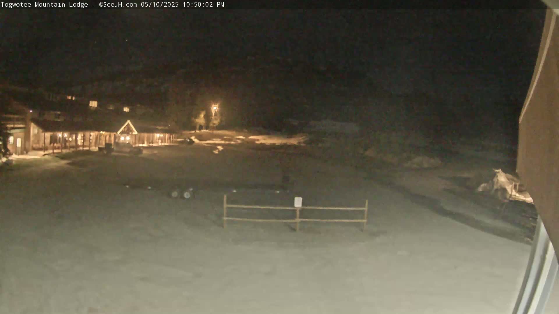 A nighttime view of a snow-covered lodge and its grounds, illuminated by artificial light.
