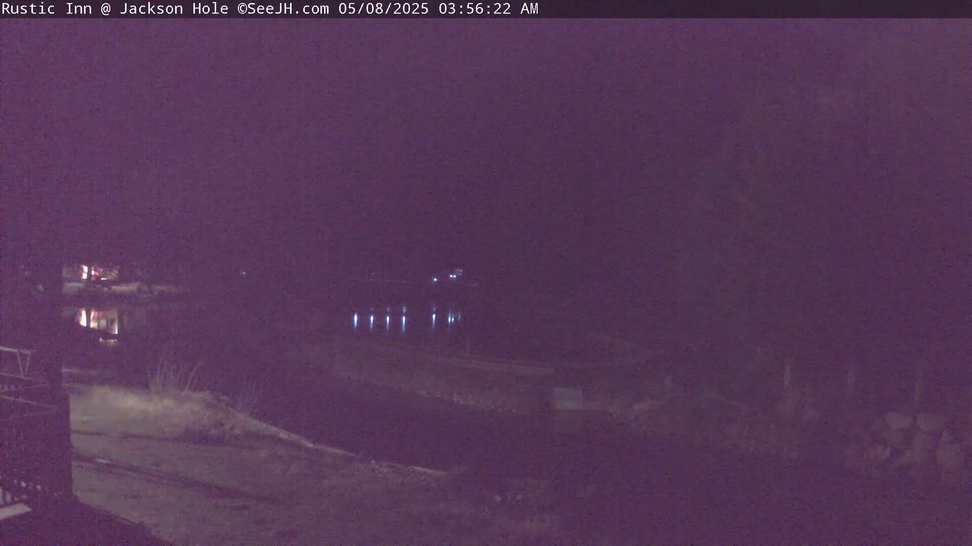 A dark, nighttime scene shows a body of water reflecting faint lights across its surface.