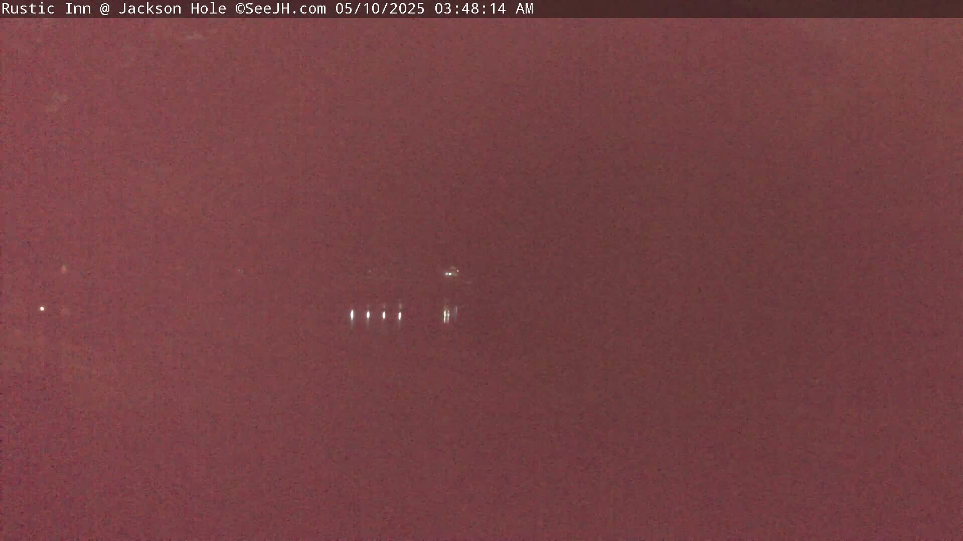 A dark reddish-brown, possibly nighttime, outdoor scene shows a few distant lights in the center.