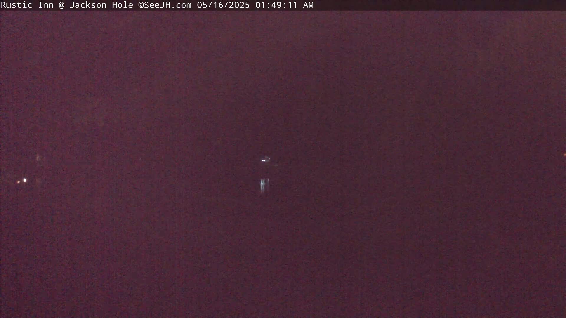 A dark, nighttime image shows a few faint lights in the distance.