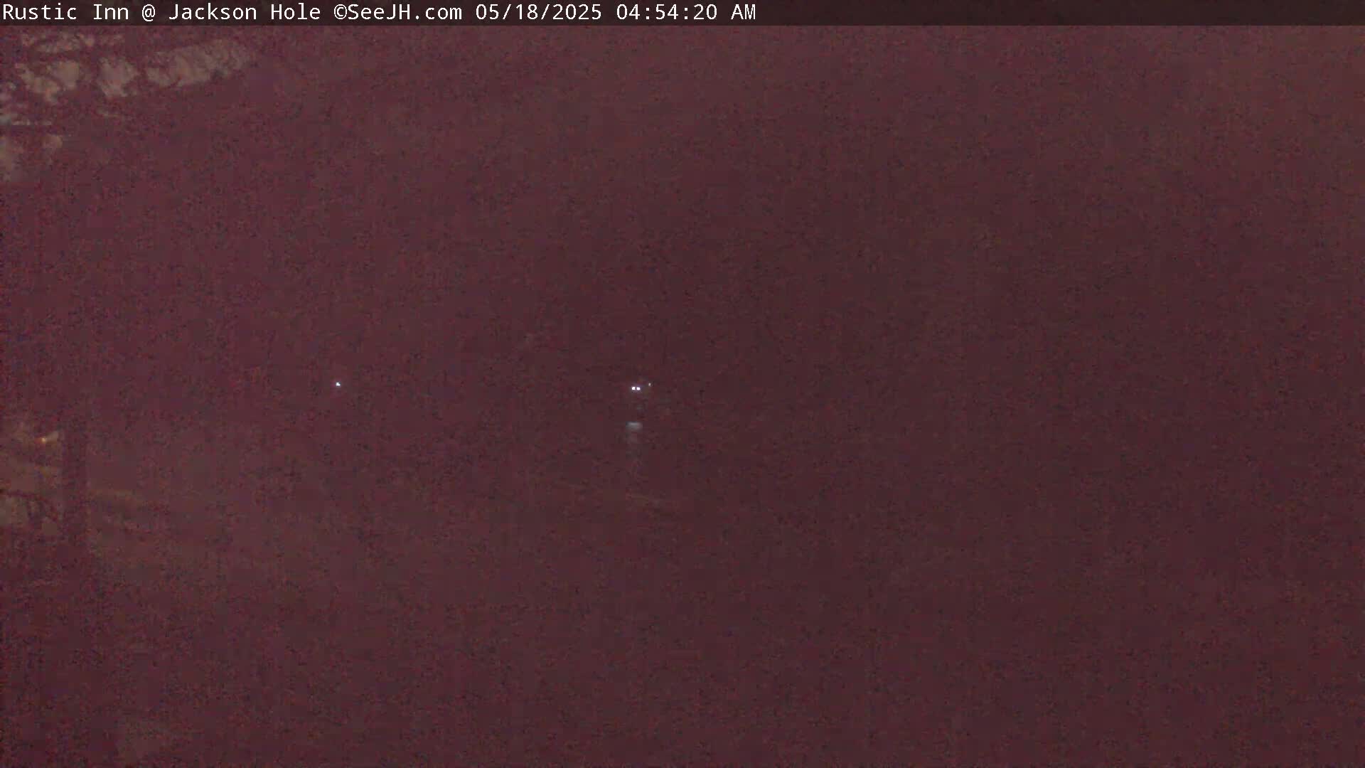 A dark, hazy nighttime scene shows a pair of distant headlights on a road.