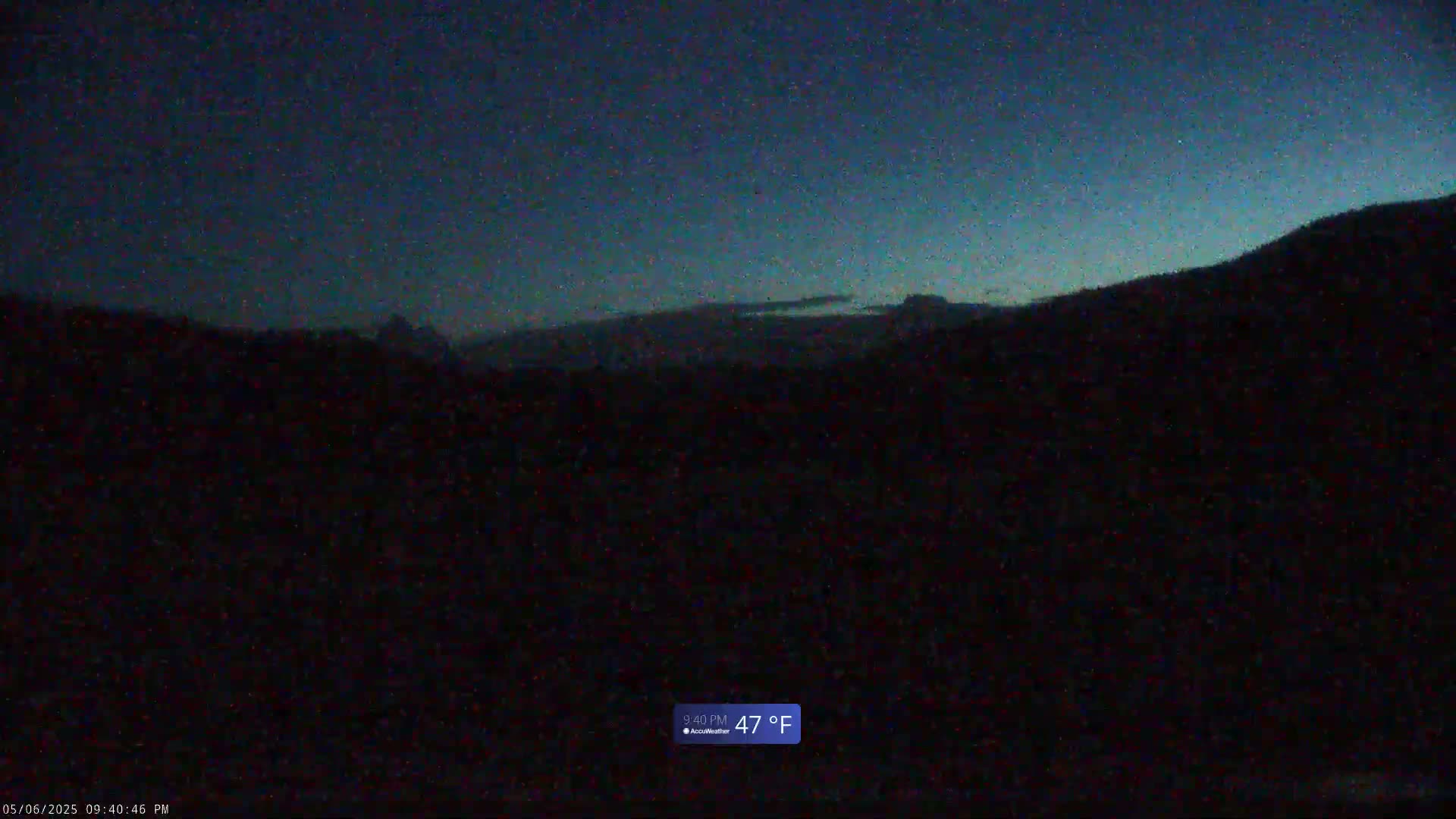A dark, mountainous landscape is visible under a twilight sky.