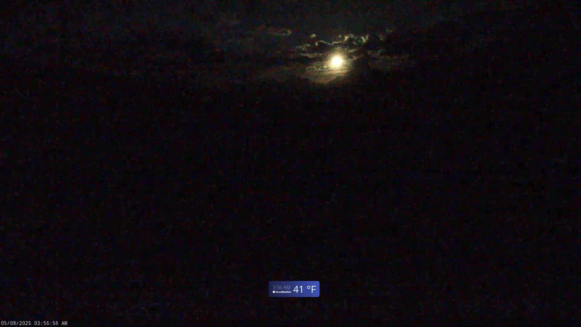A bright moon shines through a partly cloudy night sky.