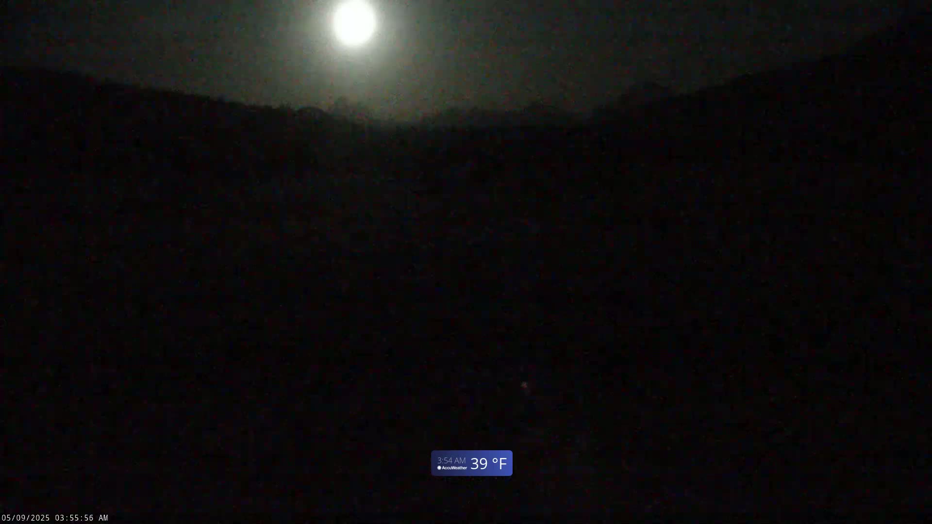 A bright moon illuminates a dark, hilly landscape at 39°F under a clear night sky.