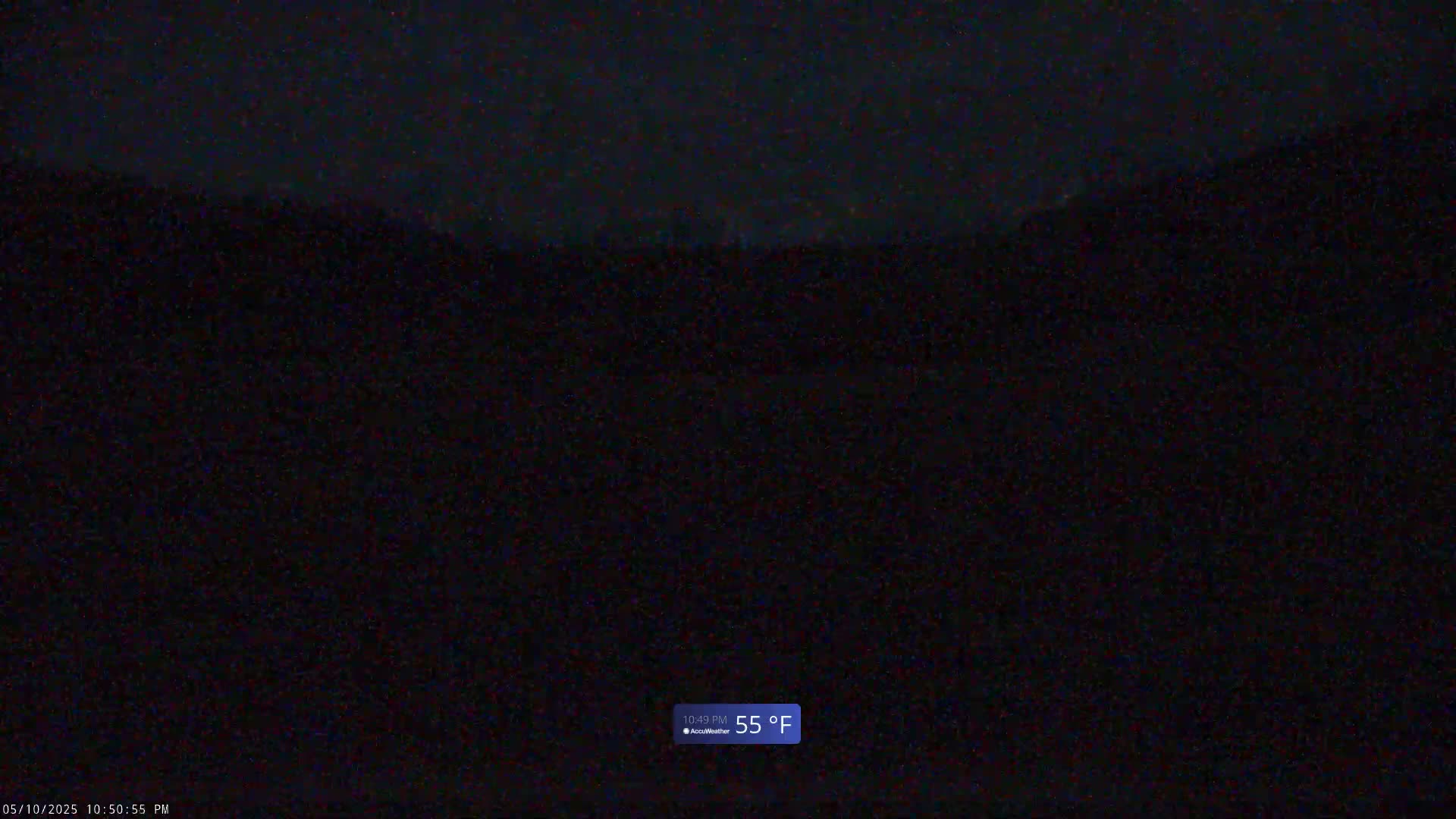 A dark, nighttime outdoor scene shows a blurry, indistinct landscape under a seemingly clear sky, with the temperature shown as 55°F.