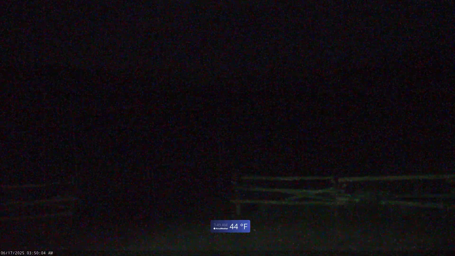 A dark, nighttime scene shows a wooden fence in the lower center, with a temperature of 44°F.