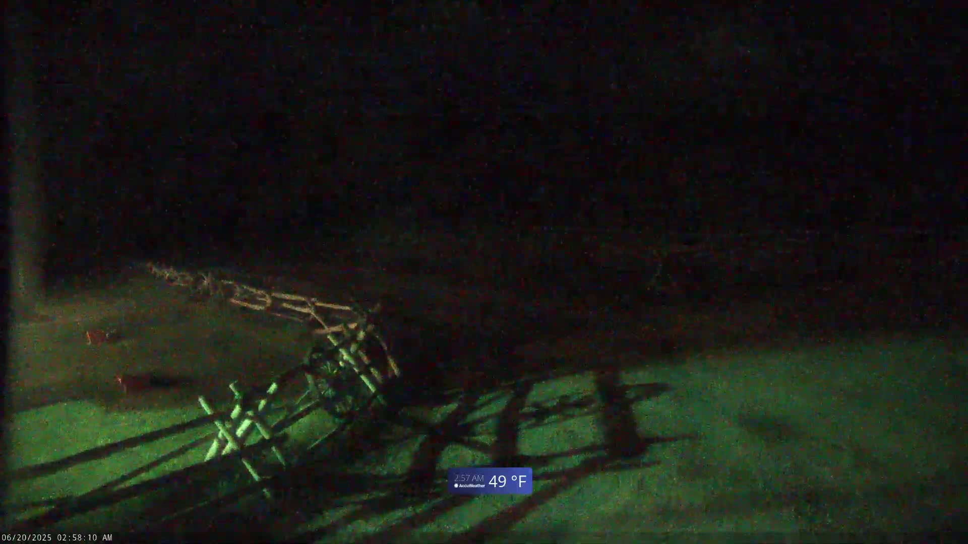 A dark, nighttime scene shows a wooden fence with long shadows cast on the ground, the temperature is 49°F.