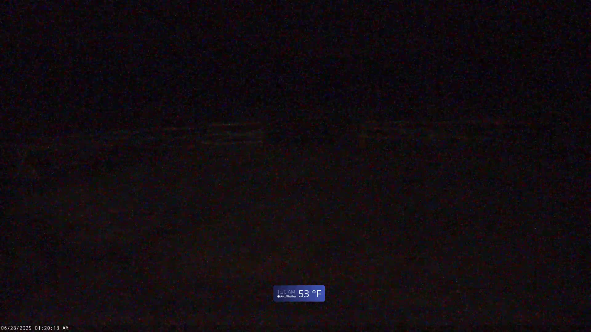 A dark, nighttime image shows a mostly black scene with faint horizontal lines suggesting a body of water under a dark sky, the temperature is 53°F.