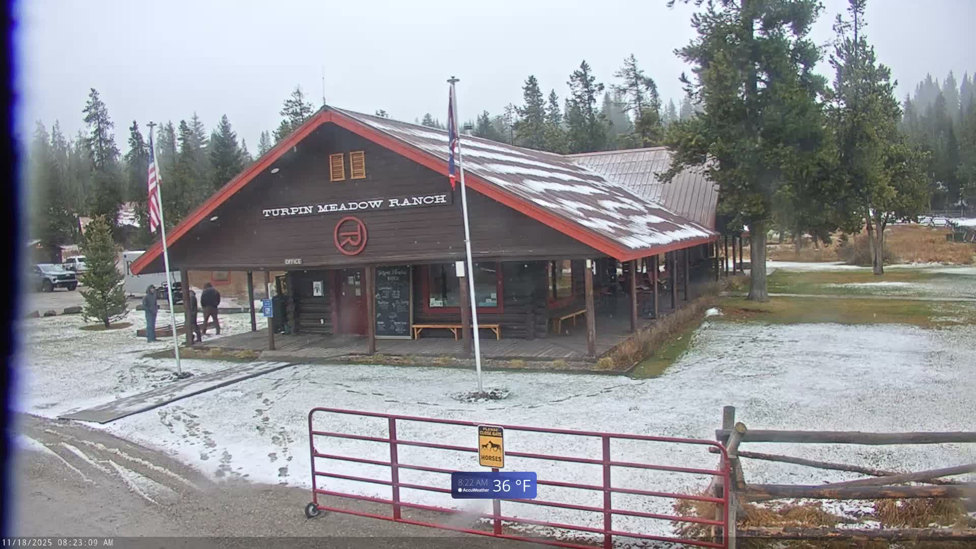 A dark outdoor scene at night, with a temperature of 41°F and clear conditions, shows a brightly lit building in the distance to the left, a tall flagpole in the foreground, and a shadowy building on the right.