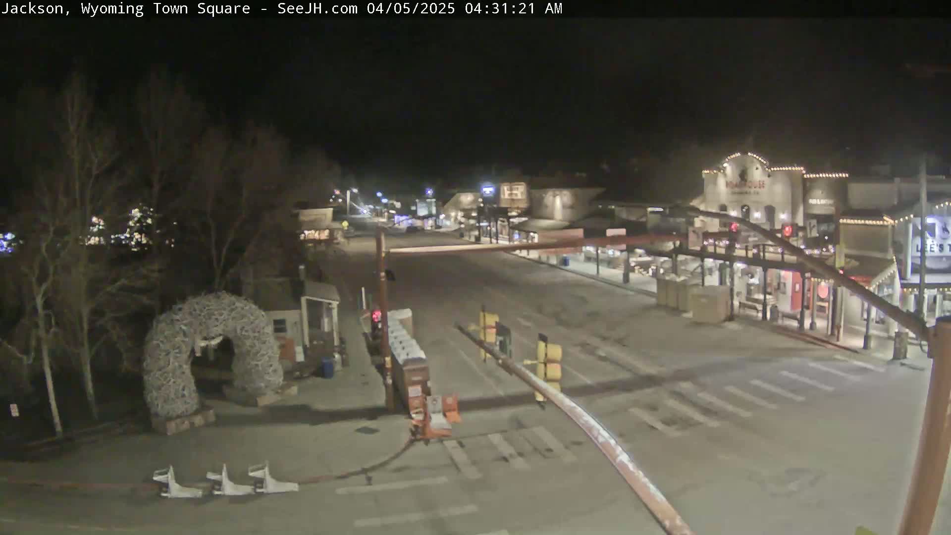 A mostly empty town square at night is lightly covered in snow.