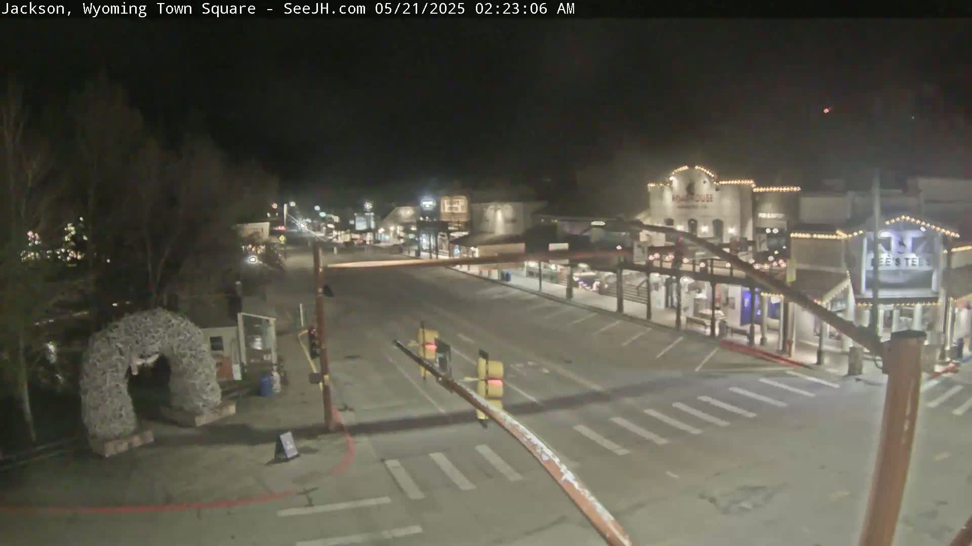 A mostly empty town square at night, illuminated by streetlights and building lights, under clear skies.