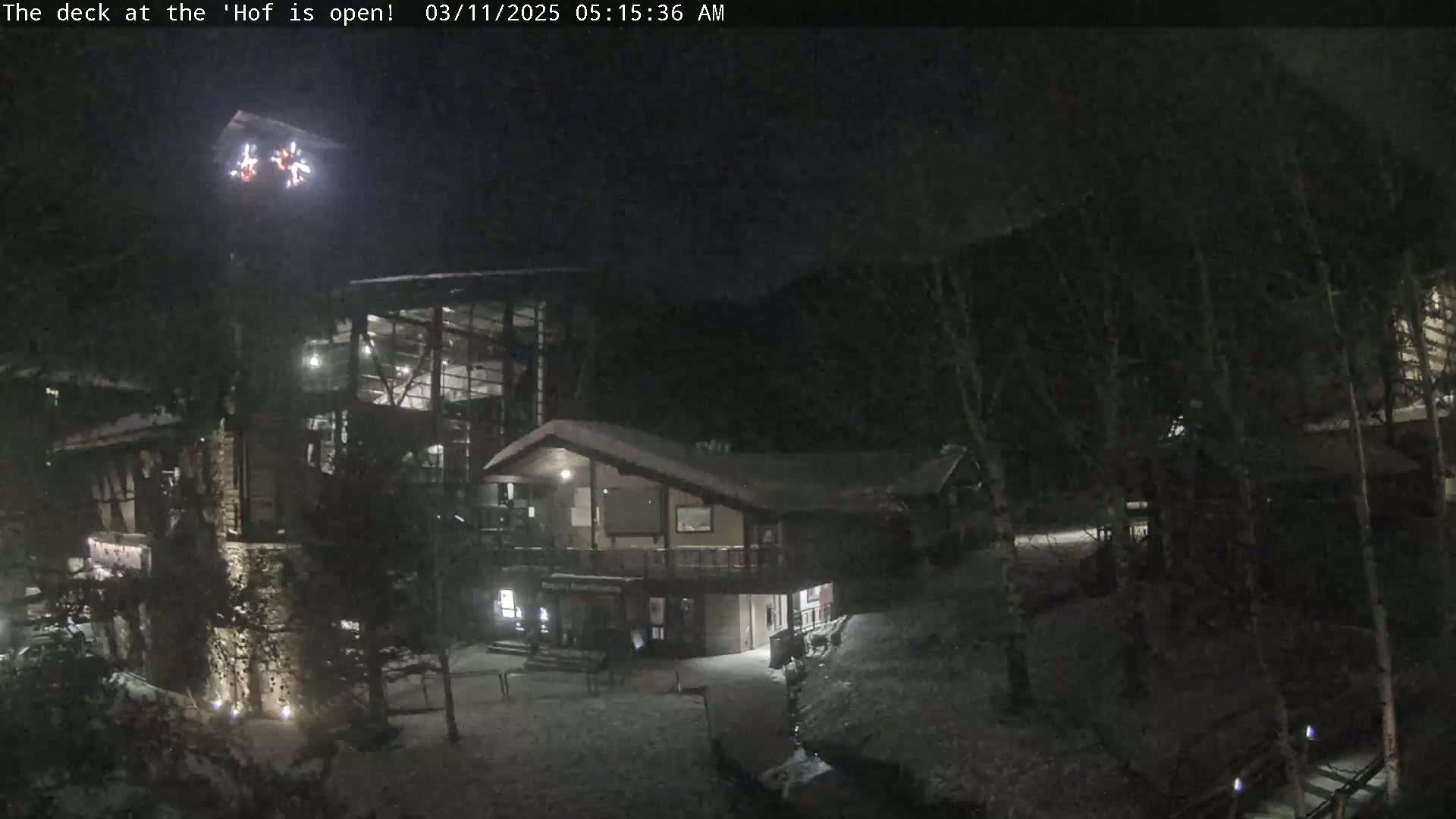A snow-covered lodge is illuminated at night, with a nighttime light display above it.