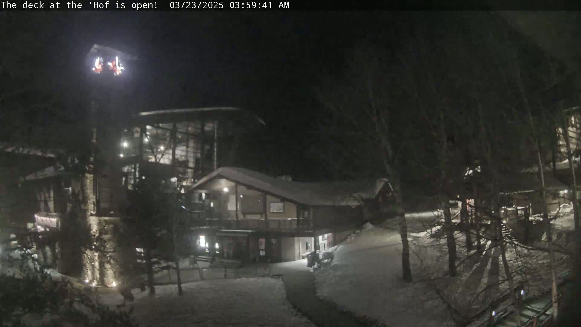 A nighttime view of snow-covered buildings and trees, illuminated by artificial lights.