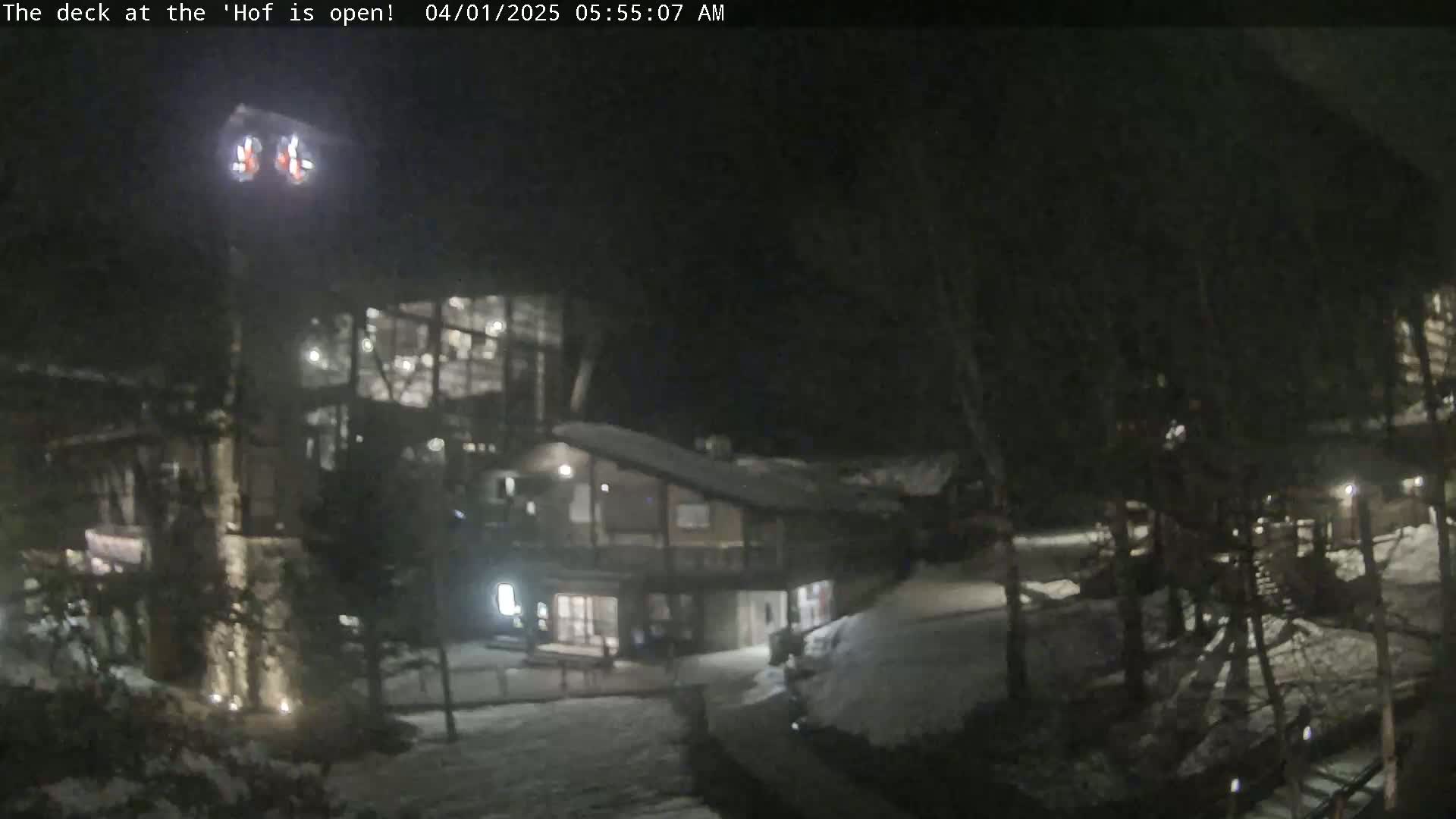 A nighttime view of a snow-covered lodge with illuminated windows and walkways.