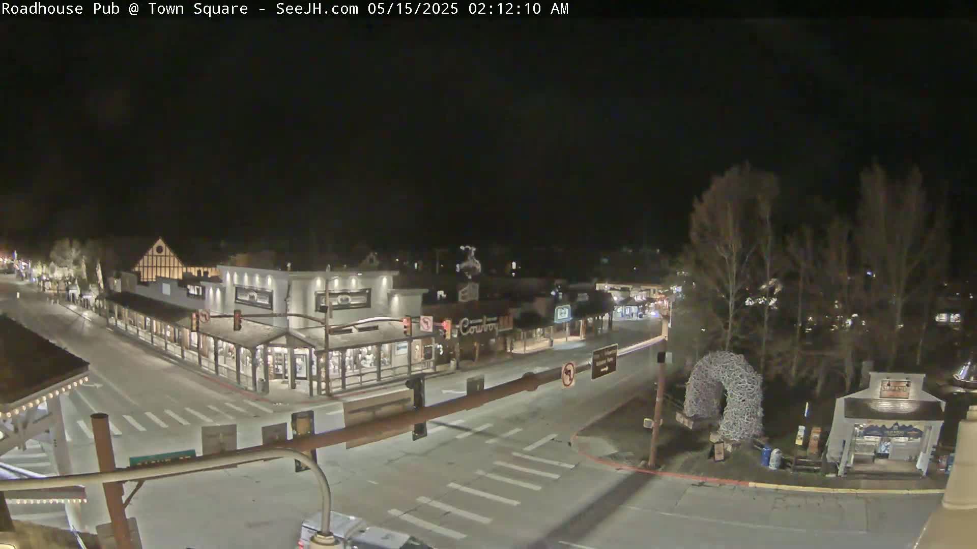 A nighttime, overhead view of a town square with several buildings and a few vehicles on the streets.