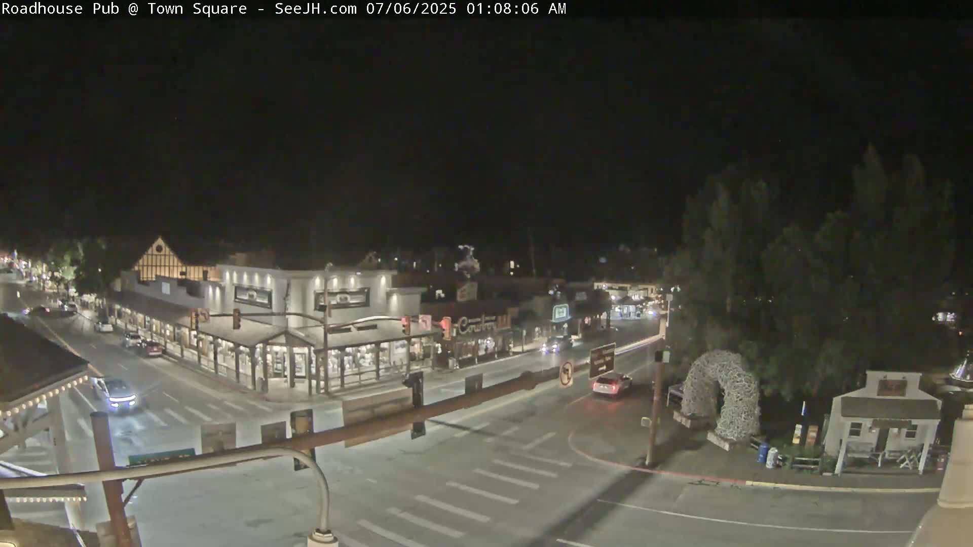 A nighttime, overhead view of a town square with several buildings and a few cars on the street.