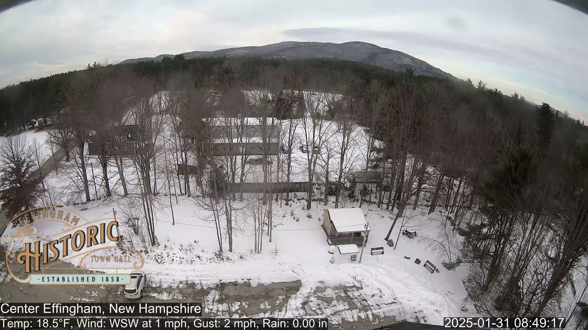 A snow-covered landscape with bare trees and several buildings is visible under an overcast sky.