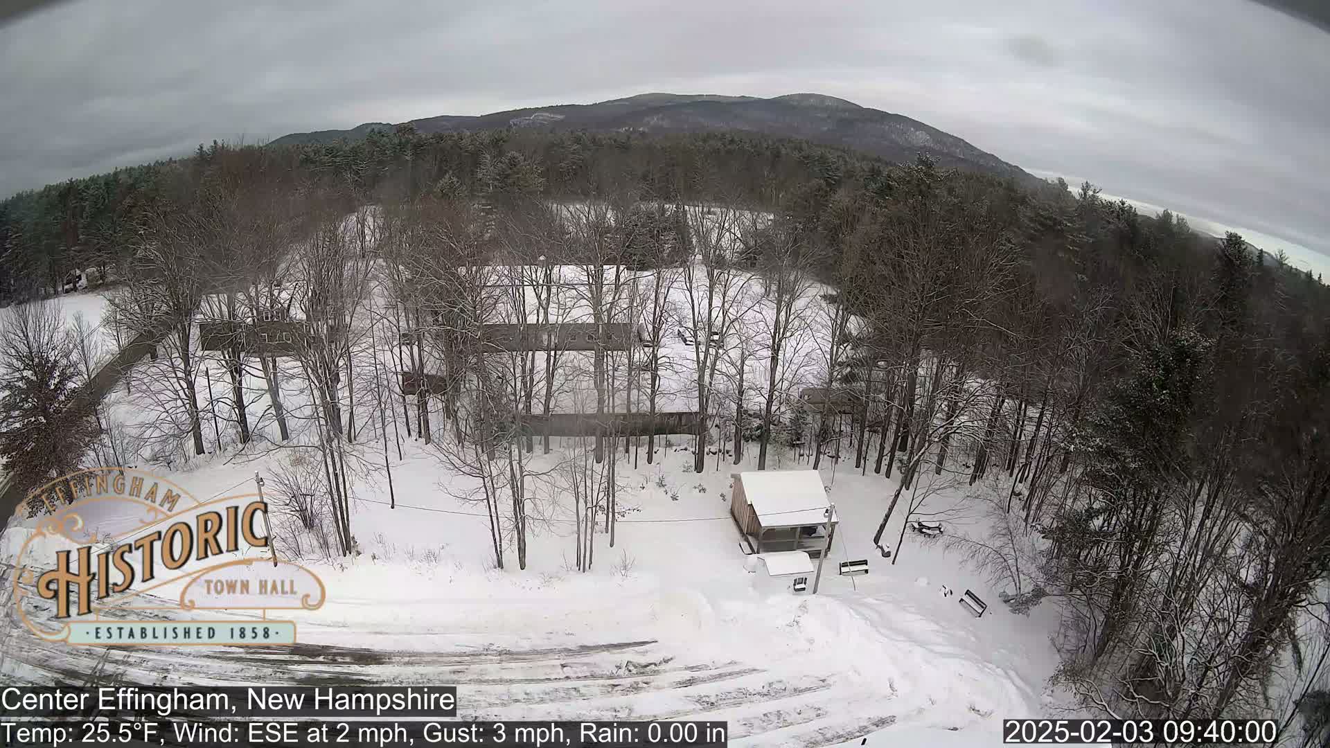 A snow-covered landscape with leafless trees and a small building is visible under a gray sky.