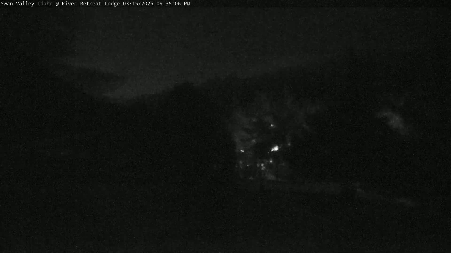 A nighttime, low-light view shows faint lights in the distance, possibly from a town or buildings, under a dark, cloudy sky.