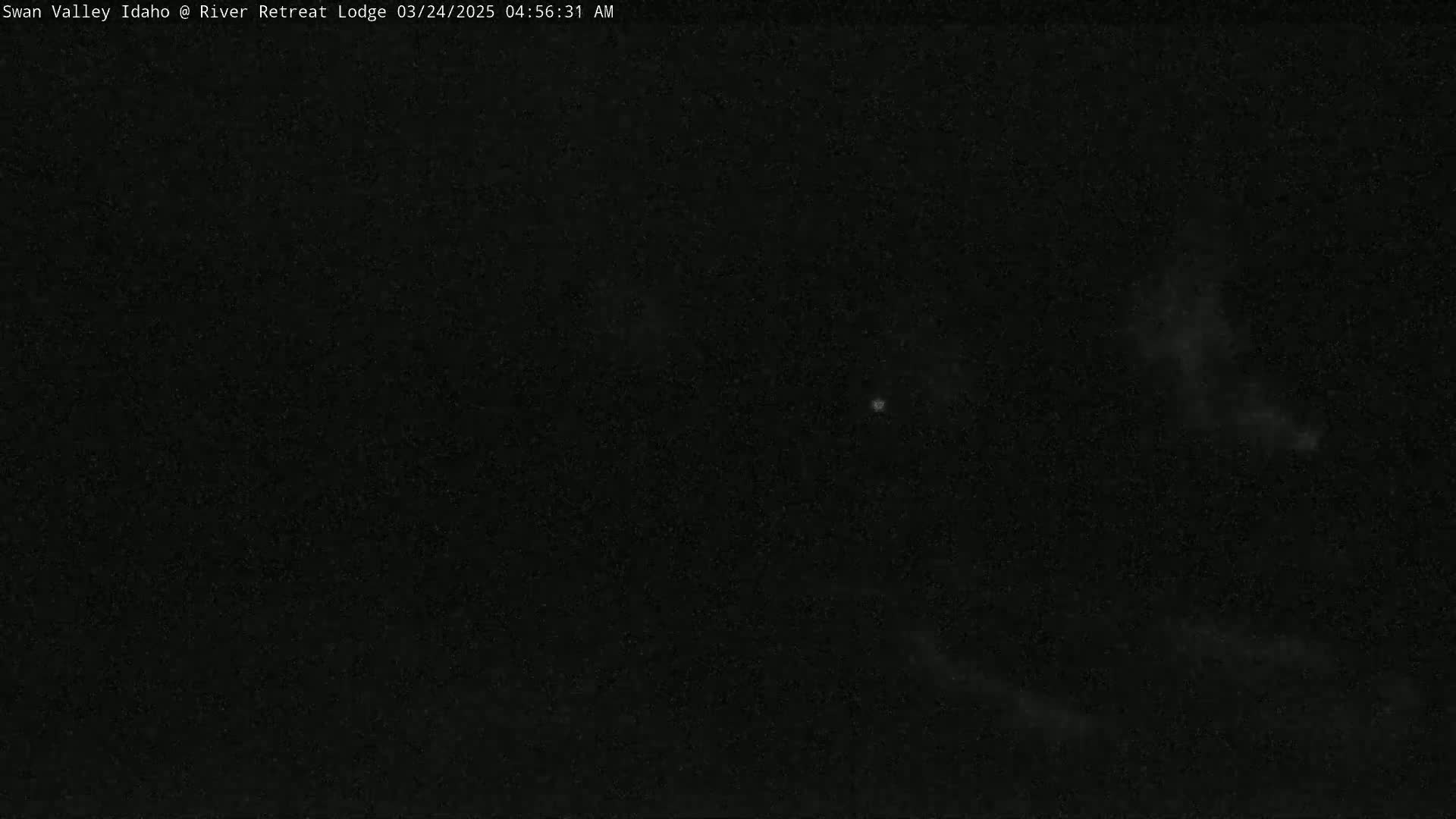 A dark, nighttime image shows a mostly clear sky with faint clouds.