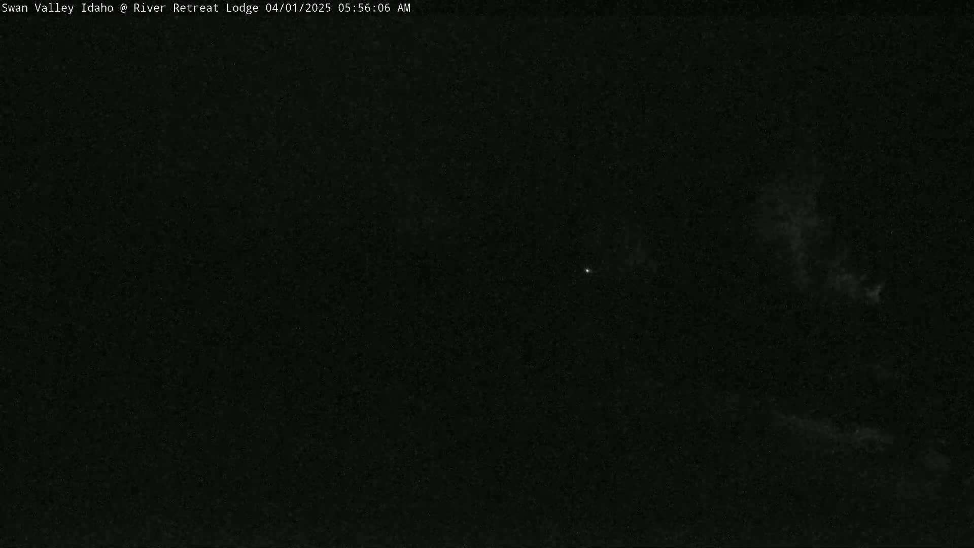A dark, nighttime scene shows a faint, bright object and some slightly lighter patches in the sky.