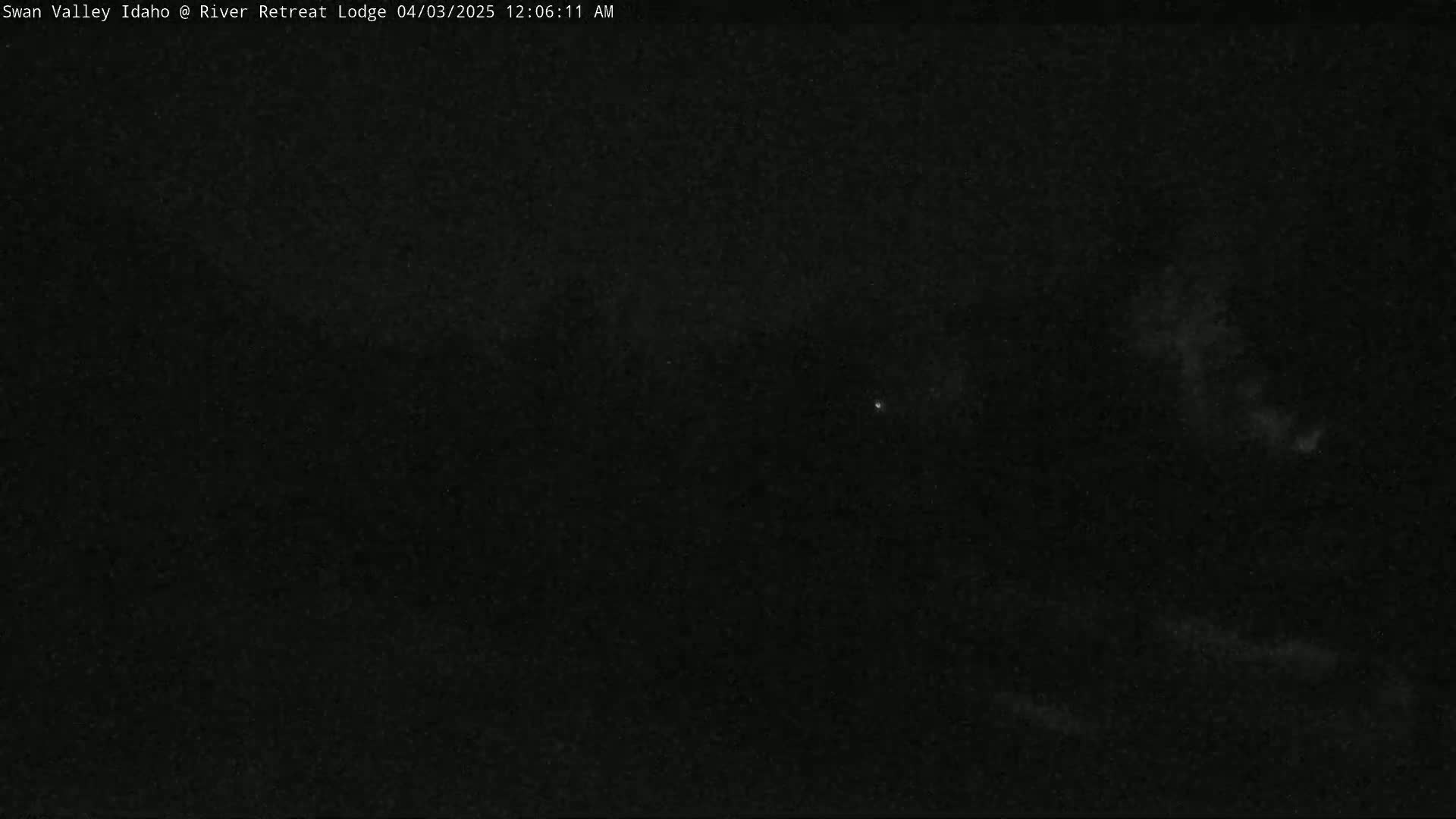 A nighttime outdoor scene shows a dark sky with faint clouds and a few very dim stars visible.