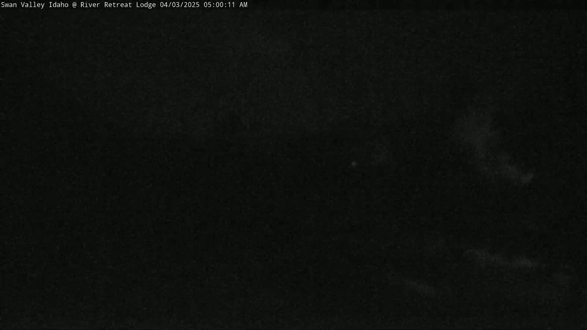 A dark, possibly nighttime, outdoor scene shows a mostly black sky with faint, indistinct light areas.