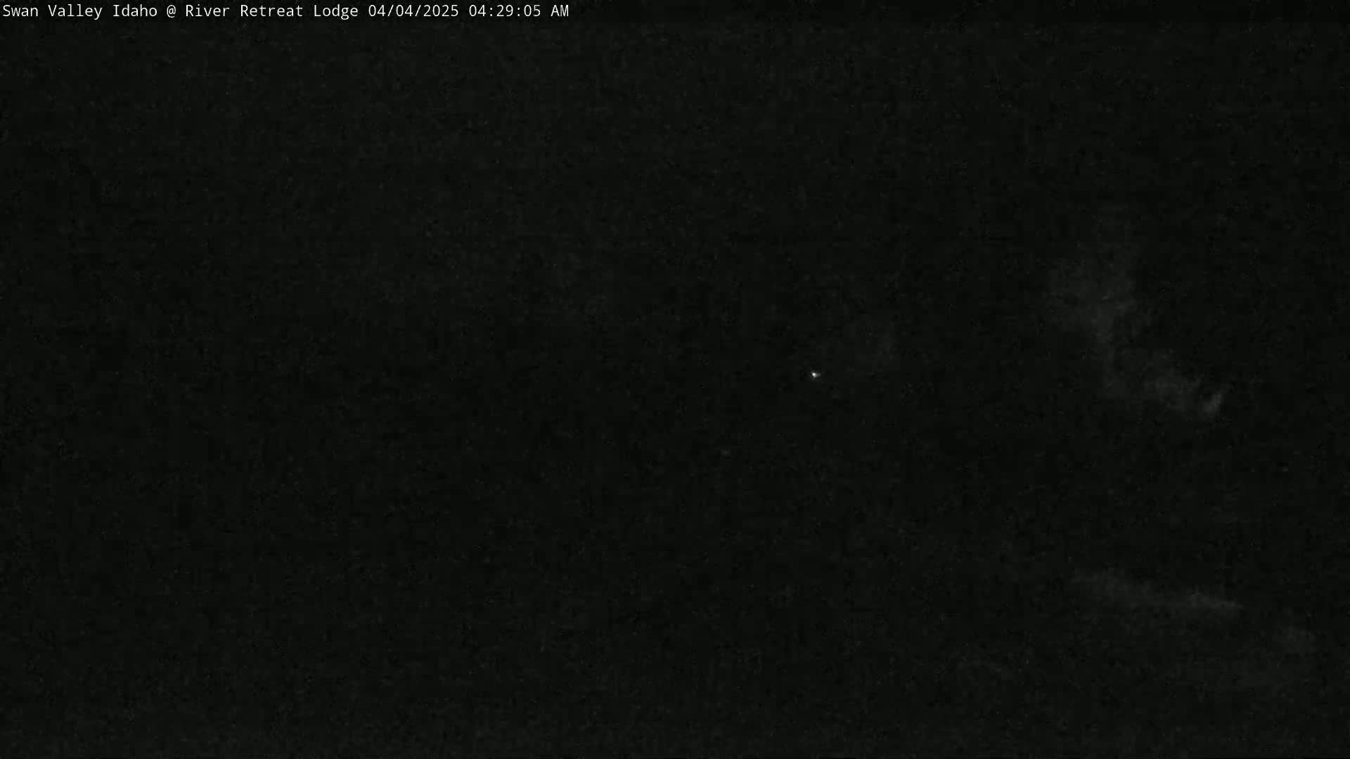 A dark, nighttime scene shows a mostly clear sky with a few faint clouds and a single bright star visible.