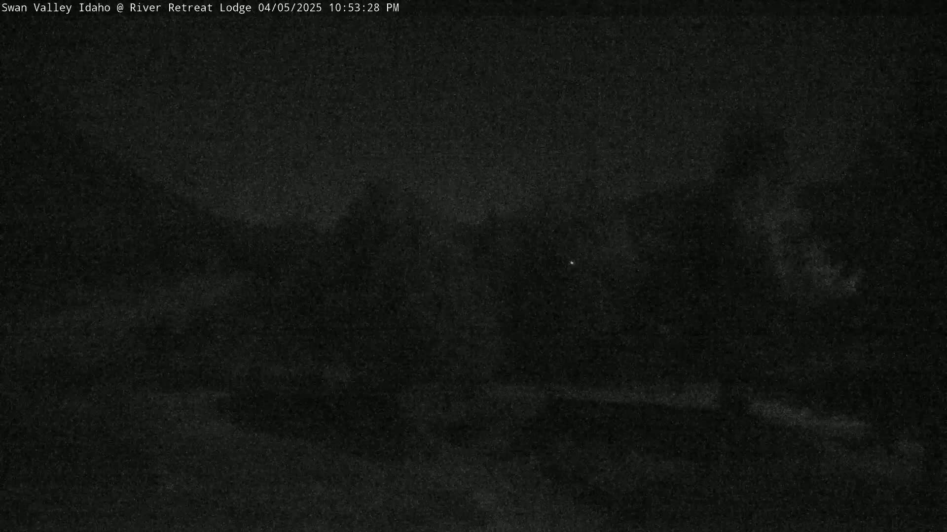A dark, nighttime outdoor scene shows a blurry, indistinct landscape under a mostly clear sky.