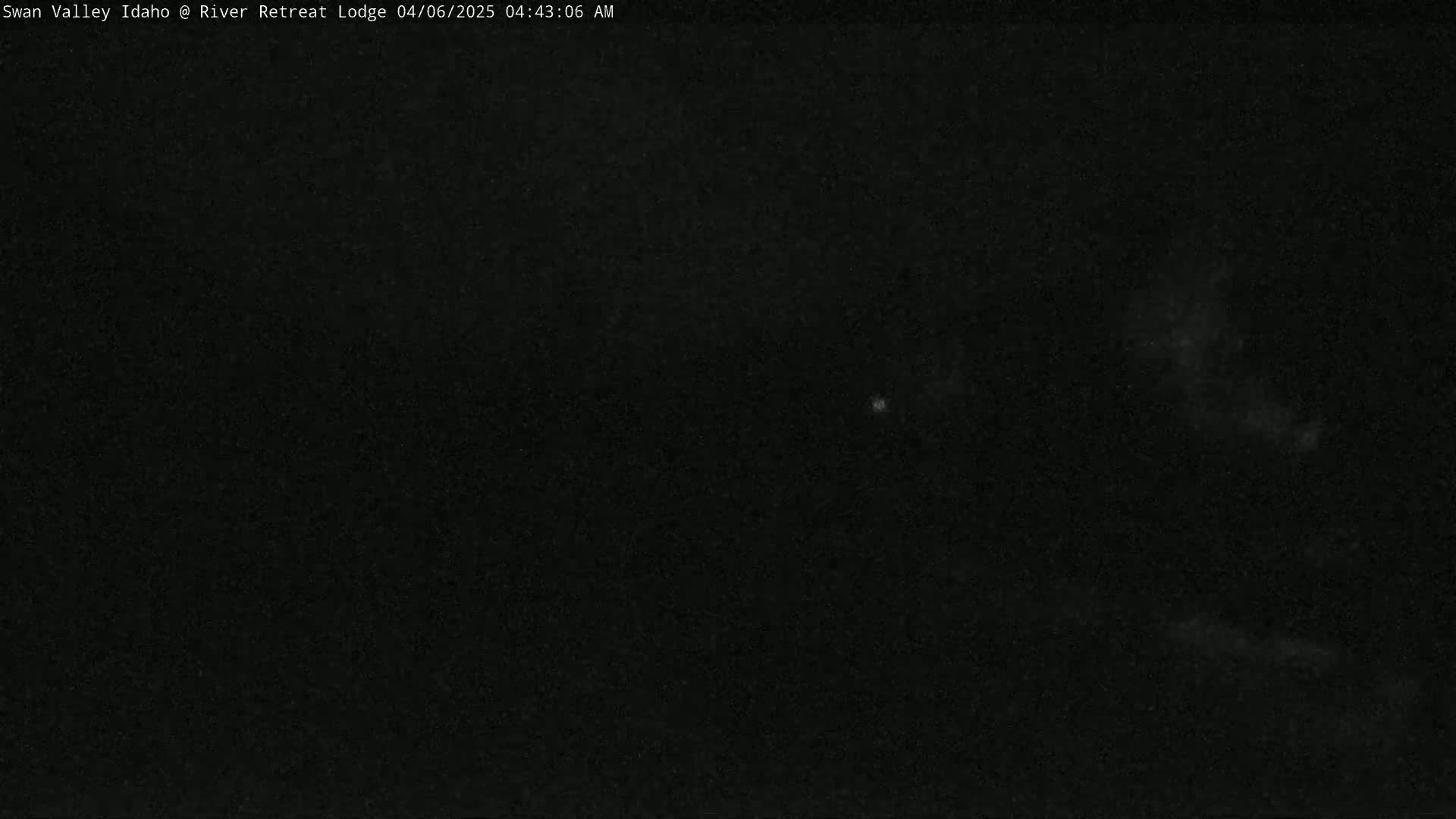A nighttime, dark image shows a mostly clear sky with a few faint, bright spots.