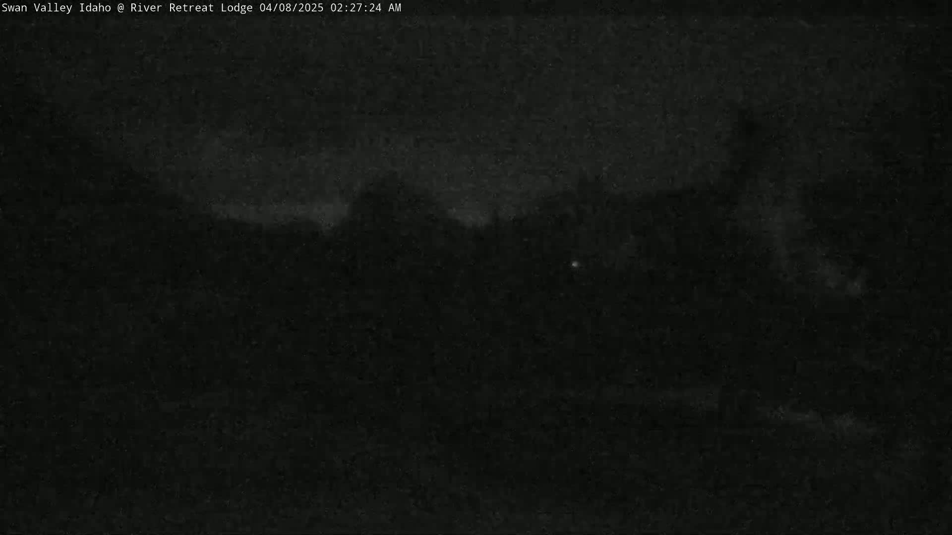 A dark, nighttime outdoor scene shows a mostly obscured landscape under a cloudy sky.