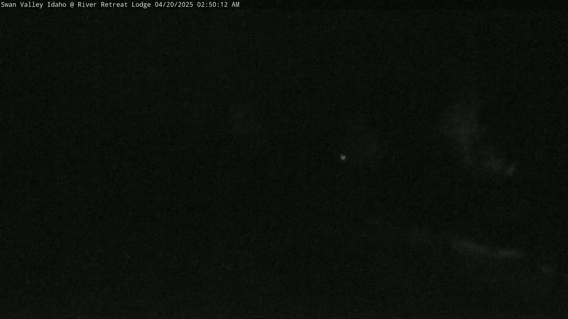 A dark, nighttime scene shows a mostly clear sky with a few faint clouds.